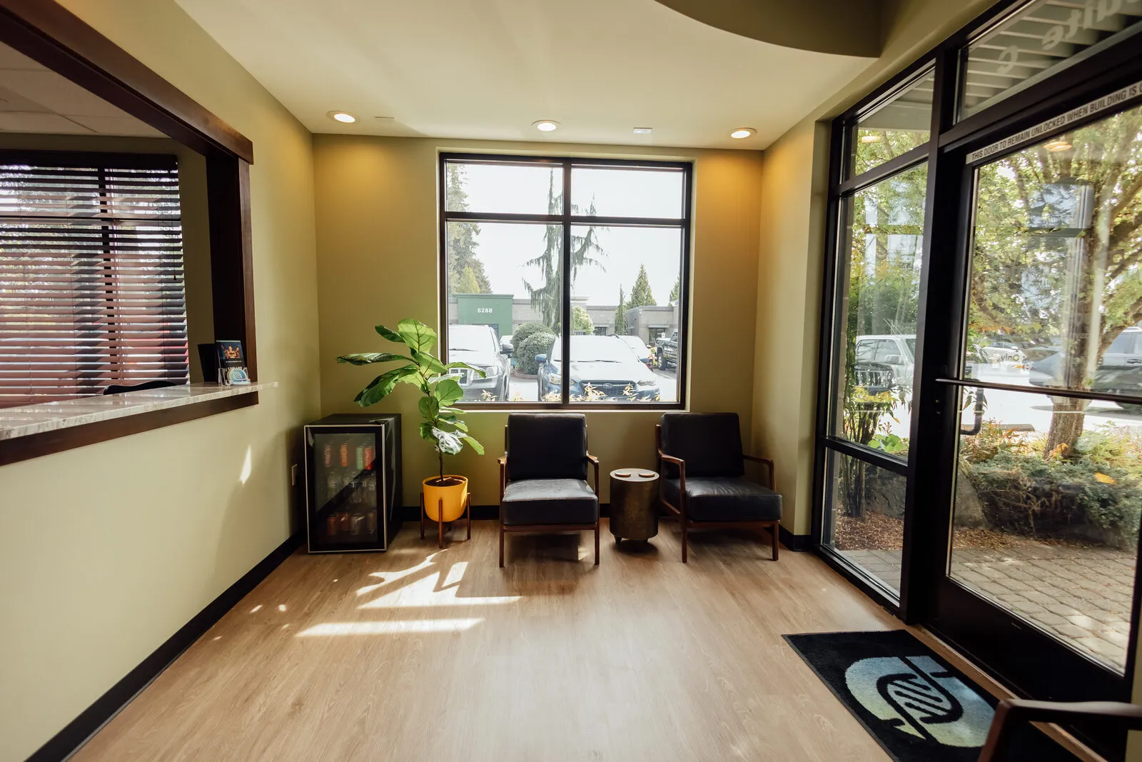 Bright waiting area inside Asymmetric Health with natural light, plants, and the asymmetric health logo on the floor