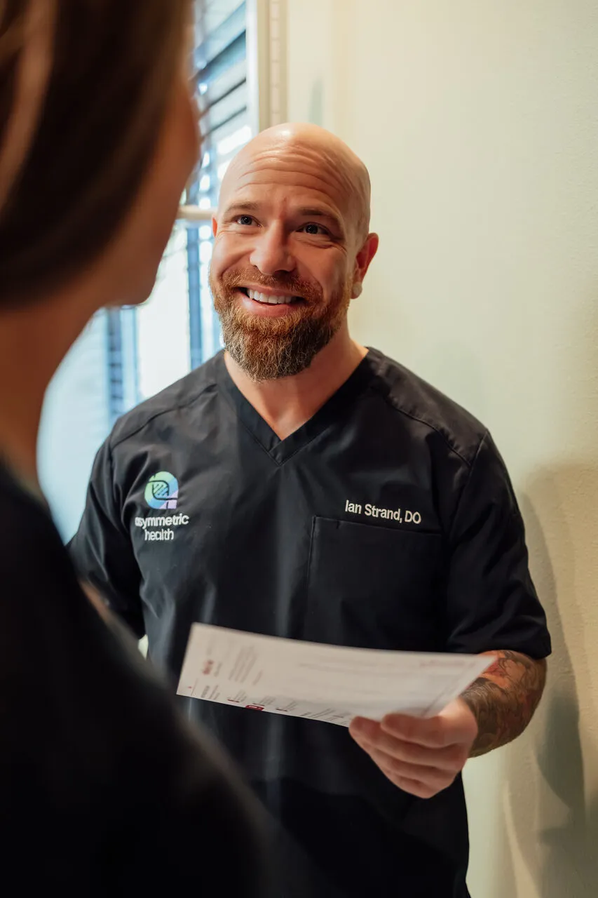 Dr. Ian Strand handing an Asymmetric Health patient her printed handout
